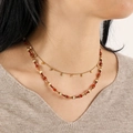 Detalle del collar de doble capa con cuentas rojas y colgantes dorados en modelo - Bendición de Cinabrio (Sin Cadena de Metal)