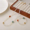 Elegant jewelry set with clear crystal beads, red agate accents, and gold Chinese motifs - Necklace And Bracelet Set