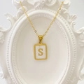 Goldene quadratische Muschel-Halskette mit Anhänger Buchstabe S auf weißem Rahmen - Buchstabe S / Weiß