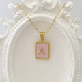 Goldene quadratische Kette mit rosa Emaille und Buchstabe A auf weißem Bilderrahmen - Buchstabe A / Rosa