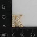 Macro shot of gold letter K pendant with clear cubic zirconia on a scale background - Letter K