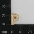 Macro shot of gold letter P charm with white zirconia inlay and millimeter scale - Letter P