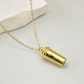 Gros plan sur la chaîne dorée avec pendentif cylindrique poli sur pierre décorative blanche - Mini Tasse de Café Dorée (Or Type E)