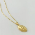 Macro detail of a gold rugby pendant necklace showing fine non-slip texture and relief seams - Gold Rugby Style
