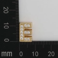 Golden letter E charm with white zircon crystals shown against a metric scale - Letter E
