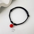 Detailed macro of a black braided bracelet with an 8.5mm red bead charm and gold ring - Red Round Bead (4 Styles, 08-0175)