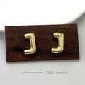 Detail view of gold letter J stud earrings showing unique fold design and precise 17.5mm size - Gold J