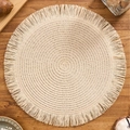Modern cream round woven placemat with delicate fringe trim on a wooden tabletop - Off White