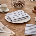 Classic blue striped cotton-linen table napkin folded on a rustic wooden dining table - White Wide Striped