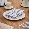 Classic black and white checkered cotton linen napkin folded on a white ceramic dinner plate - White Large Grid