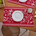 Detailansicht roter Jacquard-Tischsets mit Blumenmustern und Vögeln auf einem Esstisch aus Holz - Glückliche Vögel & Blumen