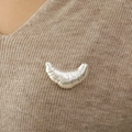 Silberne Croissant-Brosche mit geripptem Design auf einem braunen Strickpullover - Silber