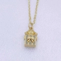 Detailed close-up of a gold gift box pendant with an elegant bow on a necklace - Gold