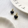 Detail of black heart earrings with gold base and clear zircon accents on white fabric - Style A - Black Heart