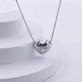 Macro shot of silver heart pendant with letter C on white tiered display stand - Silver C