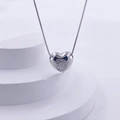 Macro shot of silver heart pendant with letter D diamond inlay on white stairs - Silver D