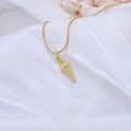 Macro shot of gold conch shell pendant on fine chain over white fabric texture - Conch / Style A