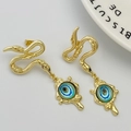 Detailed close-up of golden snake stud earrings with blue evil eye charms on white plate - Sky Blue (Style C)