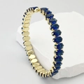 Détail d'un bracelet doré avec des zircons bleus à coupe ovale et sertissage à quatre griffes - Bleu foncé