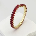 Gros plan d'une bague dorée avec un cercle complet de zircons rouges ovales sertis - Rouge