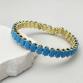 Détail d'un bracelet doré orné de zircons ovales bleu vif avec un sertissage à griffes - Bleu