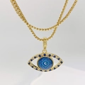 Detalle macro del colgante ojo de la suerte dorado con cristales azules y cadena box - Estilo con Patrón Mandala (Estilo B)