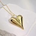 Macro detail of a 3D heart-shaped gold pendant resting on a textured white stone base - Large Heart Pendant (Style B) / Style B Gold