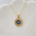 Collana dorata con ciondolo a lettera M in smalto blu su vassoio a forma di conchiglia - Lettera M / Blu