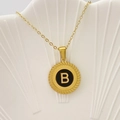Elegante collana dorata con pendente circolare e lettera B su sfondo nero lucido - Lettera B / Nero