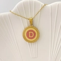 Collana dorata con ciondolo lettera D e smalto rosa su un vassoio di conchiglie - Lettera D / Rosa