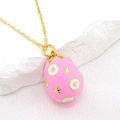 Macro shot of pink enamel egg pendant with gold stars and white dots on silk background - Pink