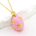 Detail of pink enamel Easter egg pendant with gold daisy relief on a textured stone - Pink
