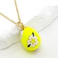 Close-up of yellow enamel Easter egg pendant with white floral patterns on gold O-chain - Yellow