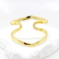 Golden open cuff bracelet with wavy lines and hammered texture on white stone base - Gold