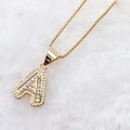 Luxury gold letter A pendant necklace with sparkling cubic zirconia on white fur background - Gold A