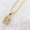 Close-up of gold letter P pendant with zircon pavé setting on white plush background - Gold R