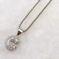 Macro detail of silver letter G pendant necklace with sparkling cubic zirconia inlay - Silver G
