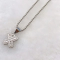 Macro detail of silver X-shaped pendant with cubic zirconia pave and box chain - Silver X