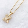 Gold plated letter Z pendant necklace with zircon stones on white faux fur background - Gold Z
