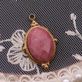 Detail eines ovalen rosa Natursteinanhängers mit vergoldeter Perlenkante aus Edelstahl - 15x24mm / Rhodonit