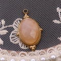 Detail eines facettierten ovalen Edelsteinanhängers mit goldenem Perlenrahmen - 15x24mm / Rosa Aventurin