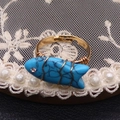 Primer plano de anillo artesanal de turquesa con forma de pez y alambre dorado ajustable - Turquesa Azul