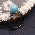 Close-up of handmade silver wire wrapped ring featuring a light blue natural stone bead - Amazonite