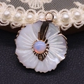 Detailed macro view of a peach blossom shell pendant with opal inlay and gold plating - Opal
