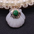 Macro detail of fan-shaped shell pendant with turquoise inlay and gold plated metal edges - Malachite
