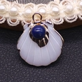 Detailed view of scallop shell pendant with blue gemstone inlay and gold metal base - Lapis Lazuli