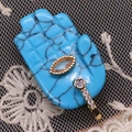 Macro view of blue Hamsa hand pendant with gold accents and sparkling crystal stones - 17x32mm / Blue Turquoise