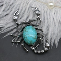 Détail d'une broche scorpion vintage avec pierre turquoise sur un fond de plumes douces - 40x55mm / Turquoise Bleue