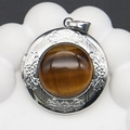 Macro shot of a vintage silver locket featuring a round Tiger Eye stone and floral engraving - Tiger's Eye