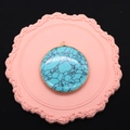 Detail of round turquoise pendant with gold plated edge and black web pattern on pink base - Blue Turquoise